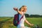 Young beautiful woman rides on a bicycle in the summertime on the green fields background and stretched out hand in the air