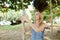 Young beautiful woman riding swing and making selfie by smartphone, sand and trees in background.