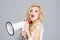 Young beautiful woman screaming in megaphone,  on background studio portrait. Shout and scream girl.