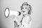 Young beautiful woman screaming in megaphone, isolated on background studio portrait. Shout girl speaks in a loudspeaker