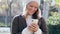 Young beautiful woman sending messages with her smart phone while staying in a park in autumn.