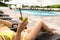 Young beautiful woman in sexy yellow swimsuit lying on lounger suntanning at hotel swimmingpool drinking cocktail on