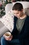 Young beautiful woman with short hair enjoying cup of tea, sitting in front of christmas tree. Authentic family xmas