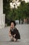 A young beautiful woman in short summer dress posing on a city street with her small cute mops dog