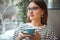 Young beautiful woman sit at table in cafe drink coffee wait for businesspartner good morning concept