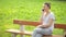 Young beautiful woman sitting on a bench in the city park and speaking on the phone and smiling