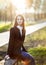 Young beautiful woman sitting on a bench in sun light on sunset