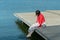 Young beautiful woman sitting on a bridge by the lake, legs down