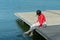 Young beautiful woman sitting on a bridge by the lake, legs down