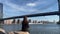 Young beautiful woman sitting on stones at embankment in Dumbo, Brooklyn.