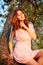 Young beautiful woman sitting on a tree in blooming gardens