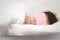 Young beautiful woman sleeping in bed with eye mask in the morning. Woman resting in comfortable white bed, lying on