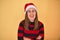 Young beautiful woman smilling happy wearing striped sweater and a santa claus hat at christmas over yellow background