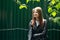 Young beautiful woman smokes outside in a black jacket