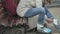 Young beautiful woman in sporty warm clothes and rollers, sitting on a wooden bench and dresses roller skates getting