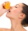 Young beautiful woman squeezes orange on white bacground