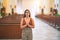 Young beautiful woman standing with hands together praying at church