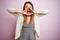 Young beautiful woman standing over pink isolated background Shouting angry out loud with hands over mouth