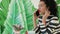 Young, beautiful woman in a striped suit talking on the phone on the background of green leaves