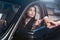 Young beautiful woman in suit sitting in driver seat of car and receiving coffee from