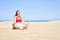 Young beautiful woman sunbathing and relaxing sitting on the sand doing yoga poses at maspalomas dunes bech
