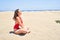 Young beautiful woman sunbathing and relaxing sitting on the sand doing yoga poses at maspalomas dunes bech