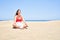 Young beautiful woman sunbathing and relaxing sitting on the sand doing yoga poses at maspalomas dunes bech