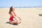 Young beautiful woman sunbathing and relaxing sitting on the sand doing yoga poses at maspalomas dunes bech