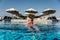 Young beautiful Woman sunbathing in swimming pool at luxurious looking on sunshade parasol in Egypt Luxor