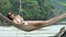 Young beautiful woman in sunglasses relaxing on the hammock on tropical beach