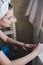 Young beautiful woman with towel on her head after shower in bathroom applies nail polish. The concept of female morning