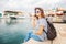 young beautiful woman traveler in a hat talking on a mobile phone on a beautiful port background on a sunny day by the sea.