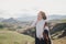 Young beautiful woman traveler wearing hat and poncho relaxing on the top of the hill