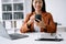 Young beautiful woman typing on tablet and laptop while sitting at the working white table modern office