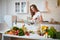 Young beautiful woman using a notebook while cooking in the modern kitchen. Healthy food and Dieting concept. Losing Weight