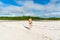 Young beautiful woman walking on the beach sand towards the trees and the mangrove