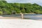 Young beautiful woman walking on the beach sand towards the trees and the mangrove