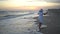 Young beautiful woman is walking by the sea at sunset. In a white dress and a white hat. The woman is pregnant. She runs away from