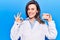 Young beautiful woman wearing dentist coat holding denture doing ok sign with fingers, smiling friendly gesturing excellent symbol