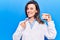 Young beautiful woman wearing dentist coat holding denture smiling happy pointing with hand and finger