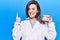 Young beautiful woman wearing dentist coat holding denture smiling with an idea or question pointing finger with happy face,
