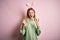 Young beautiful woman wearing easter rabbit ears standing over isolated pink background shouting with crazy expression doing rock