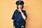 Young beautiful woman wearing police uniform asking to be quiet with finger on lips