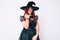 Young beautiful woman wearing witch halloween costume beckoning come here gesture with hand inviting welcoming happy and smiling