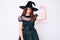 Young beautiful woman wearing witch halloween costume strong person showing arm muscle, confident and proud of power