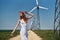 Young beautiful woman in a white dress in a field near a windmill in summer, nature