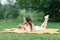 A young beautiful woman in a white dress sits on a blanket on a summer picnic on the green grass. Happy spending time in nature in