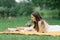 A young beautiful woman in a white dress sits on a blanket on a summer picnic on the green grass. Happy spending time in nature in