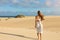 Young beautiful woman with white dress walking on desert dunes at sunset. Girl walking on golden sand on Corralejo Dunas,