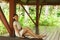 Young and beautiful woman in white dress. Woman posing in exotic Thai bungalow. Resting and traveling concept.